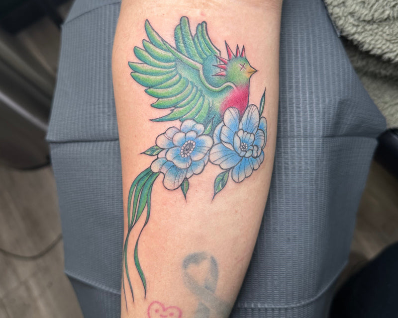 Colorful floral tattoo on a person's arm with a gray background