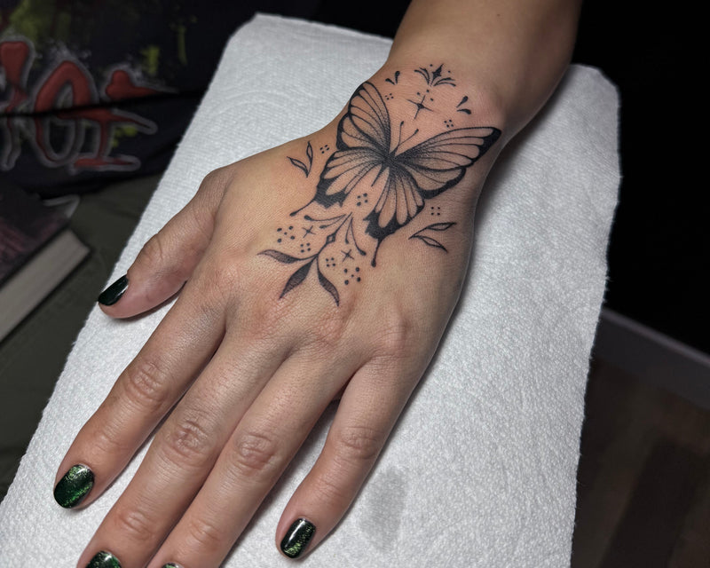 Hand with a butterfly tattoo on a white surface